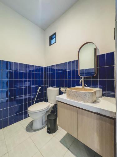 a blue tiled bathroom with a toilet and a mirror at Arunika Villa in Ciloto