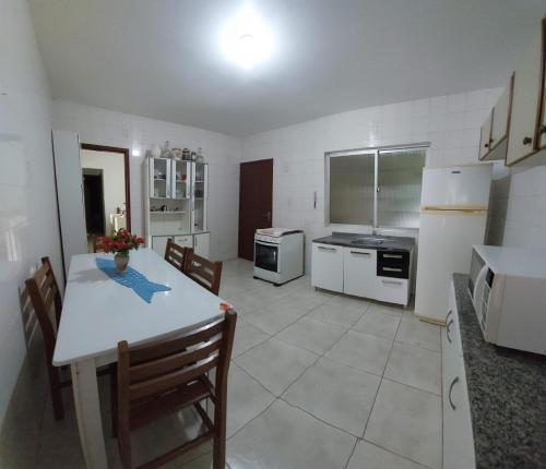 a kitchen with a table and a kitchen with white appliances at Pousada Altos dos Ingleses II in Florianópolis