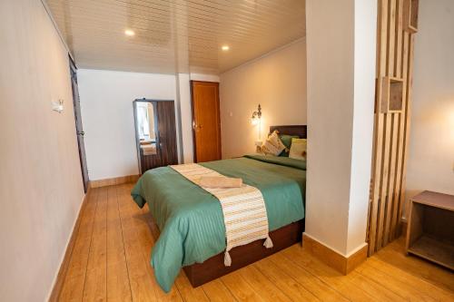 a bedroom with a bed with a green blanket at Monratino Himadrie -2 mins walk from Mall Road - All rooms have Kanchenjunga Mountain View in Darjeeling