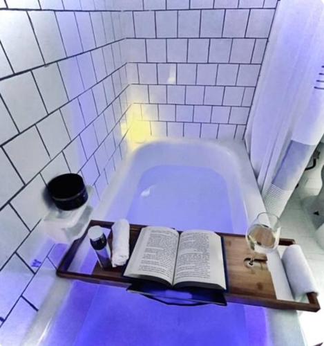 a bath tub with a book and a glass of wine at Pristine Full Sized Montrose Apartment Half Block to Menil Museum in Houston