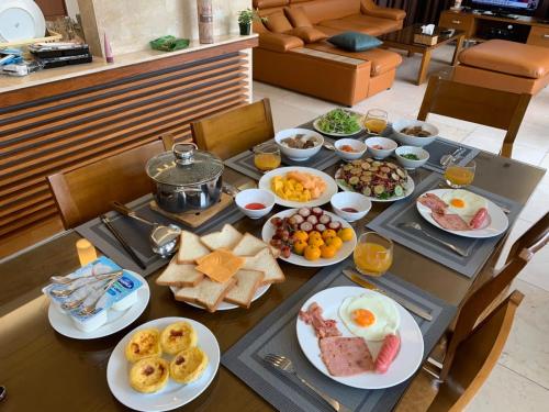 a table with plates of breakfast food on it at Amazing Newly Built Beach Pool Villas Danang in Da Nang