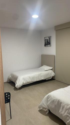 a bedroom with two beds and a chair in it at Beautiful and comfortable apartment in Bucerías