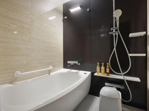 a bathroom with a white tub and a shower at MONday Apart Premium OSAKA NAMBA WEST in Osaka