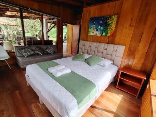 a bedroom with a large bed and a couch at Hostería CASA SAN LUIS in Mindo