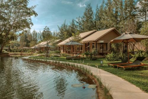 a resort with a pond in front of a building at Twinpalms Tented Camp Phuket in Bang Tao Beach