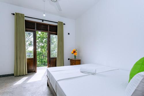 Un dormitorio con una cama y una ventana grande. en Florence cinnamon View Villa, en Kamburugamuwa