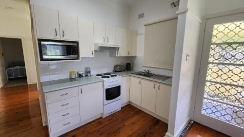 a kitchen with white cabinets and a stove top oven at Mary MacKillop Spirituality Centre Central Coast in Kincumber South