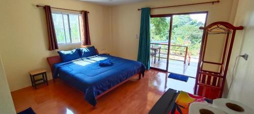 a bedroom with a blue bed and a large window at Alisa Bungalows in Ko Chang