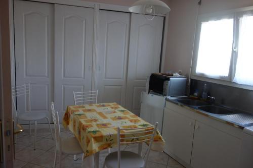 La cuisine est équipée d'une table, d'un évier et d'un four micro-ondes. dans l'établissement Logement calme confortable climatisé, à Riscle