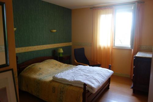 une chambre avec un lit, une chaise et une fenêtre dans l'établissement Logement calme confortable climatisé, à Riscle