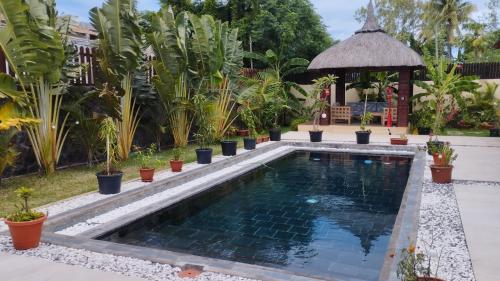 a swimming pool in a garden with a gazebo at VILLA LE DAUPHIN DU LAGON BLEU - PEREYBERE - GRAND BAIE in Grand Baie