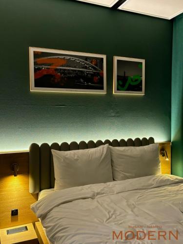 a bedroom with a bed with two pictures on the wall at Brand New Residence with Family in Busan