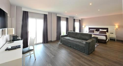 a living room with a couch and a bed at Hotel Salobreña Suites in Salobreña