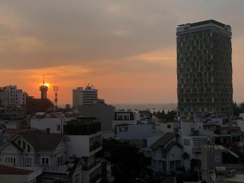 a city skyline at sunset with a tall building at Blue Sea Luxury Hotel & Apartment Vũng Tàu in Vung Tau