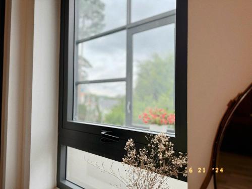 a window with a black frame and a flower arrangement at Sunflower Garden Homestay Đà Lạt in Xuan An
