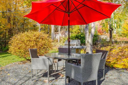 a table and chairs with a red umbrella at Lakefront Family Home with Dock in Newport! in Newport