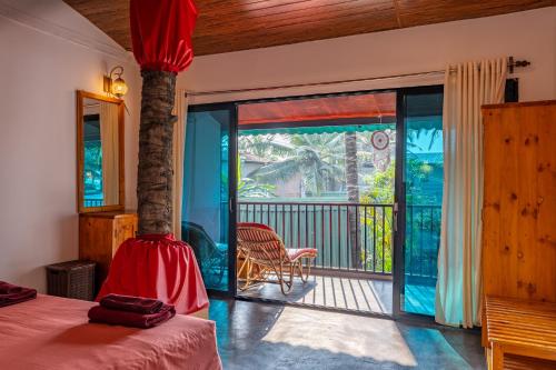 a bedroom with a bed and a view of a balcony at Simrose in Agonda
