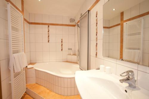 Baño blanco con bañera y lavamanos en Gasthof Hotel Engel, en Simonswald