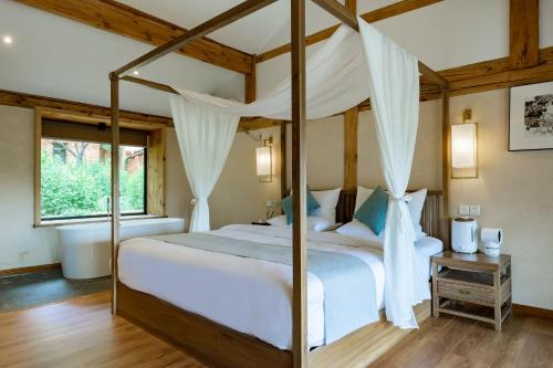a bedroom with a four poster bed and a window at Kunming Mountain Wowo Hefeng Dieyuan B&B in Kunming