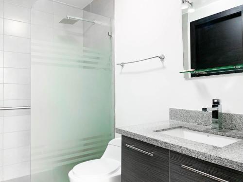 a bathroom with a toilet and a glass shower at Departamento 2 habitaciones frente al Moll del Sol in Guayaquil