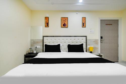 a bedroom with a large white bed with black pillows at Hotel O RichFeel in Harsola