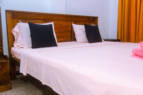 a bedroom with a large white bed with black and white pillows at Mirissa Turtle Point Guest in Mirissa