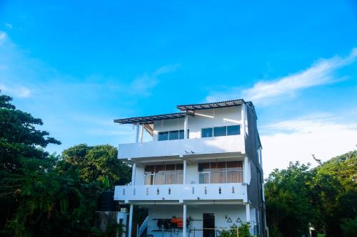 a white building with trees in the background at Mirissa Turtle Point Guest in Mirissa