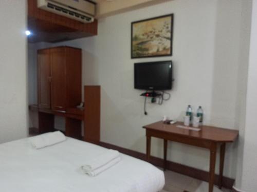 a room with a bed and a table and a tv at Hotel Ambarish Grand Residency in Guwahati