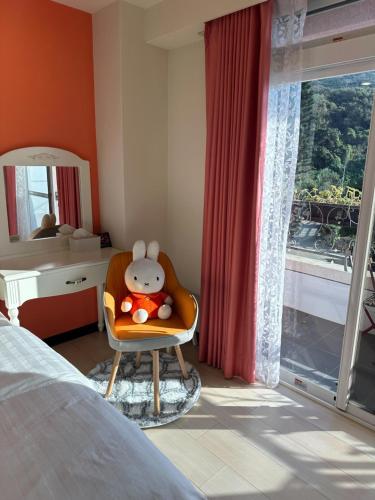 a bedroom with a chair with a stuffed animal in it at Bei Ao Bi Shan Jyu in Dongyin