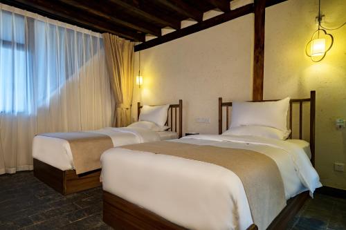 a bedroom with two beds and a window at Kunming Mountain Wowo Hefeng Dieyuan B&B in Kunming