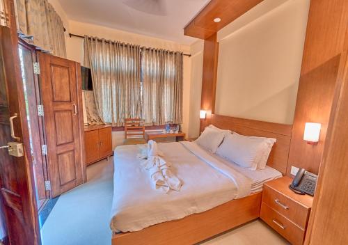 a bedroom with a large bed with white sheets at Ushasree Wayanad Pool Resort by VOYE HOMES in Ambalavayal
