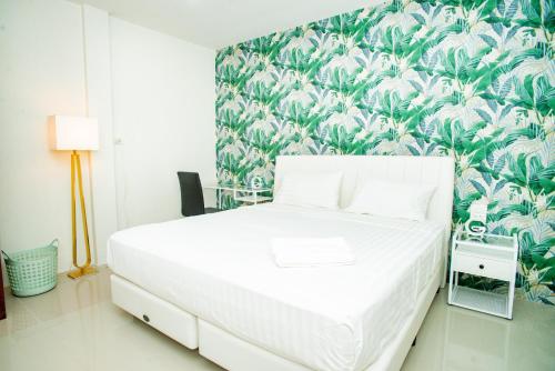 a bedroom with a white bed with a tropical wallpaper at Songbird Suites - Deluxe 2 Bedroom, 2 Bathroom Apt in Ban Khlong Haeng