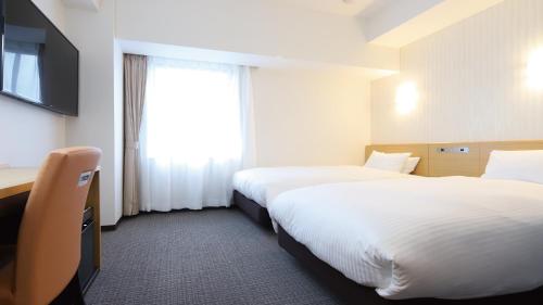 a hotel room with two beds and a television at AB Hotel Kani in Kani