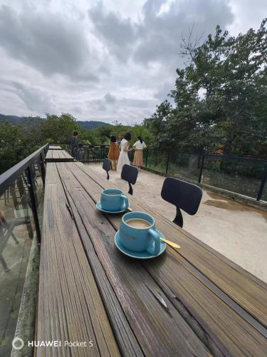 two cups of coffee sitting on a wooden table at Kunming Mountain Wowo Hefeng Dieyuan B&B in Kunming