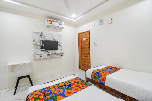 a small bedroom with two beds and a tv at FabHotel SSR Ikon Suites - Nr Hyderabad Central University, Kondapur in Hyderabad
