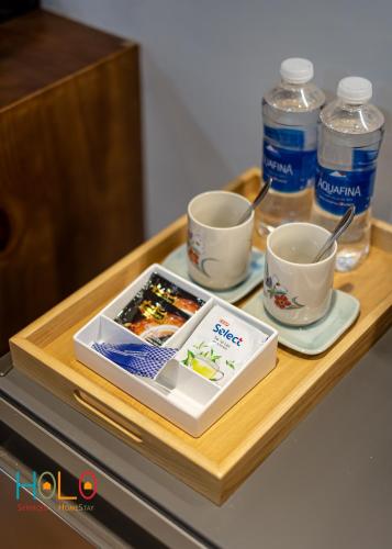 a tray with two cups and two bottles of water at HOLO HAM NGHI SAIGON - Serviced HomeStay in Ho Chi Minh City