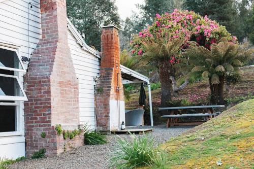 a brick house with a picnic table and a chair at Fern Mt Field on Tyenna River in Tyenna