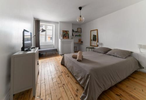 une chambre avec un grand lit et un parquet dans l'établissement Le Paradis - Appartement cœur de ville, à Clermont-Ferrand