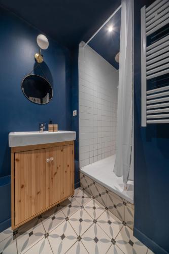 La salle de bains bleue est pourvue d'un lavabo et d'une douche. dans l'établissement Le Paradis - Appartement cœur de ville, à Clermont-Ferrand