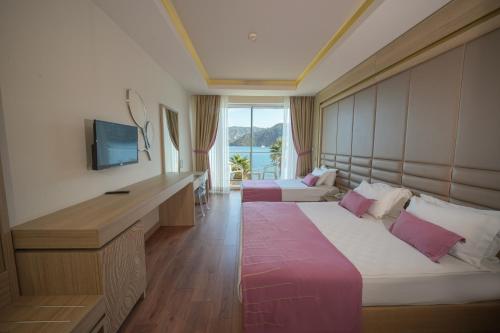 a hotel room with two beds and a television at Orka Lotus Beach in Marmaris