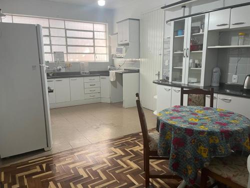 a kitchen with a table and a kitchen with white cabinets at Dodora Pousada Hostel in Bento Gonçalves