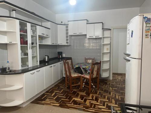 a kitchen with white cabinets and a table and a refrigerator at Dodora Pousada Hostel in Bento Gonçalves