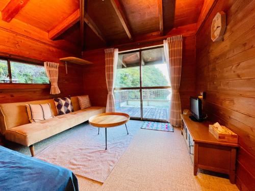 un soggiorno con un divano, un tavolo e una TV di Pension Shishikui a Shishikui