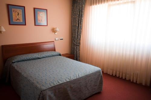 a bedroom with a bed and a large window at Hotel Restaurante La Alhama in Medina de Pomar
