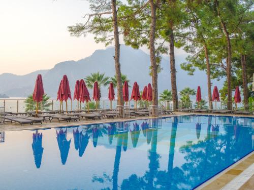 a swimming pool with red umbrellas and chairs at Orka Lotus Beach in Marmaris