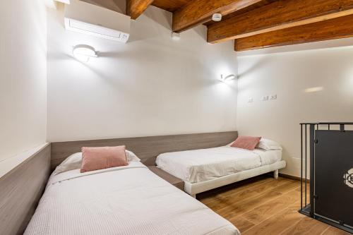 two beds in a room with white walls and wooden ceilings at Agriturismo Santa Rosa in Lubriano