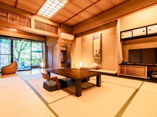 a living room with a wooden table and a television at Kirishima Momijidani Seiryuso in Kirishima