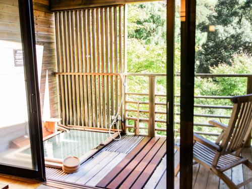 a screened in porch with a pool and a rocking chair at Kirishima Momijidani Seiryuso in Kirishima