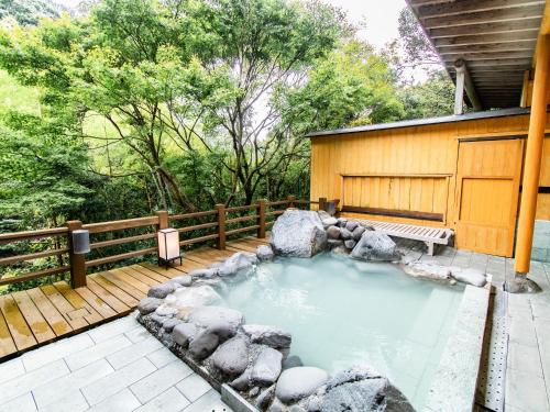 a hot tub on a deck next to a house at Kirishima Momijidani Seiryuso in Kirishima