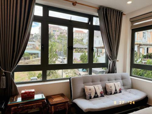 a living room with a couch and a large window at Sunflower Garden Homestay Đà Lạt in Xuan An